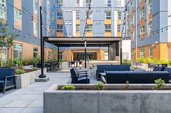 A modern outdoor seating area with a concrete planter in the foreground and a building in the background.at Traditions at Hazelwood, Oregon